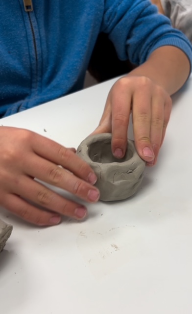 A child shaping a clay pot during a class at Altered Course Venue