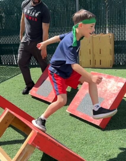 A boy stepping over an obstacle on an obstacle course