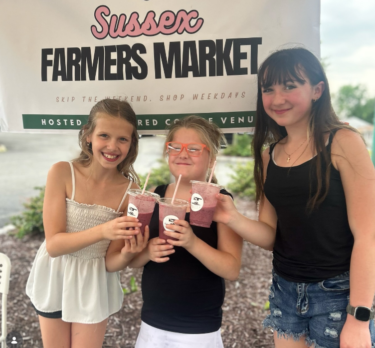 Girls enjoying smoothies at the Sussex Farmers Market, a community event Altered Course hosts